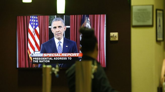 A bartender at a hotel near the Inland Regional Center watches President Obama speak on TV during the aftermath of a mass shooting that killed 14 people on Sunday