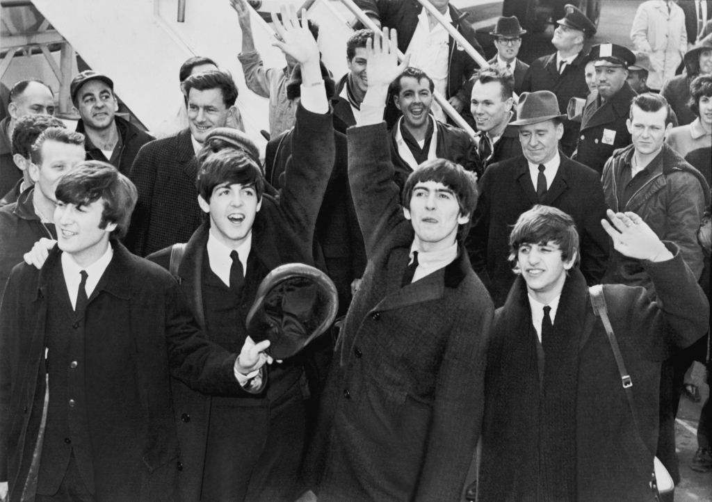 The Beatles wave to fans after arriving at the John F. Kennedy Airport in New York