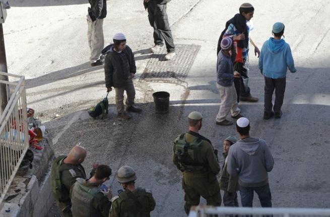 Israeli settlers gather at the site where a Palestinian attacker was shot dead after stabbing two Israelis in the Israeli occupied West Bank city of Hebron