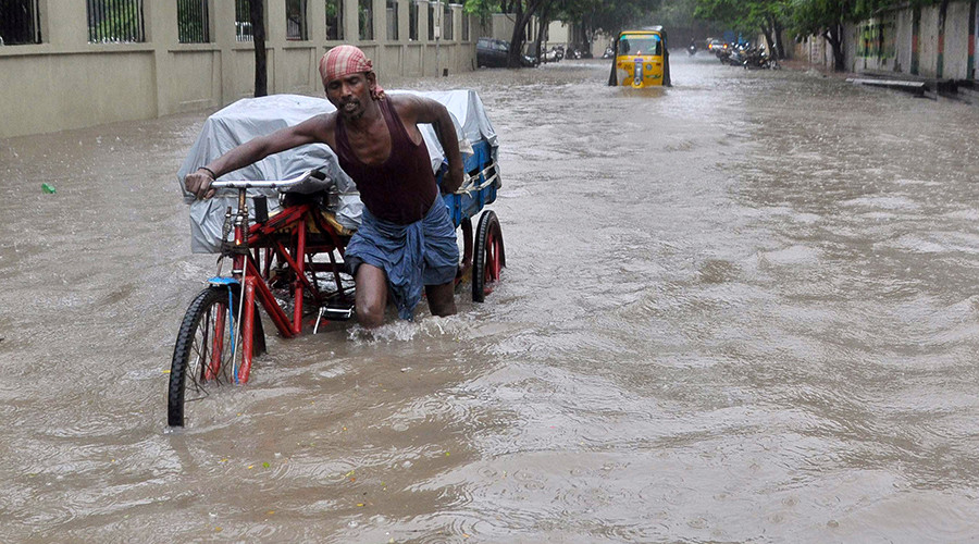 An Indian labourer pushes his cycle trishaw through floodwaters in Chennai