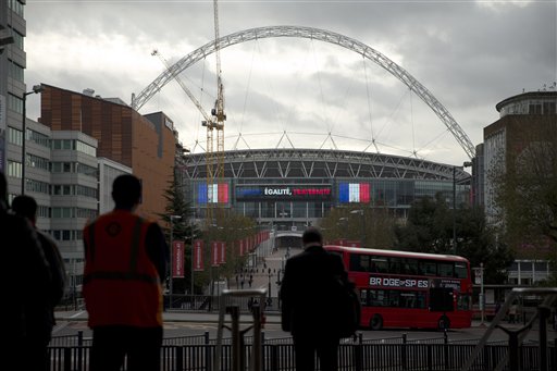 People observe a minute's silence for the victims of the deadly attacks in Paris at Wembley Park underground station in London as Wembley Stadium bearing images of two French flags and the words translated from French'Liberty Equality Fraternit