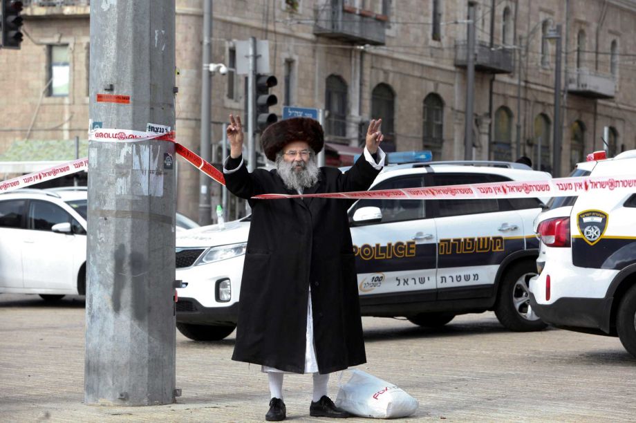 An ultra Orthodox Jew flashes victory signs at the scene of an alleged stabbing attack in Jerusalem Saturday Dec. 26 2015. According to a police spokeswoman policemen approached a man who drew their suspicions just outside the Old City for following