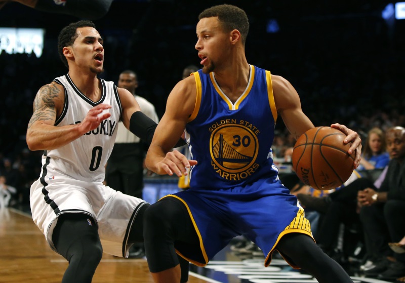 Warriors guard Stephen Curry handles the ball as he is guarded by Shane Larken of the Brooklyn Nets