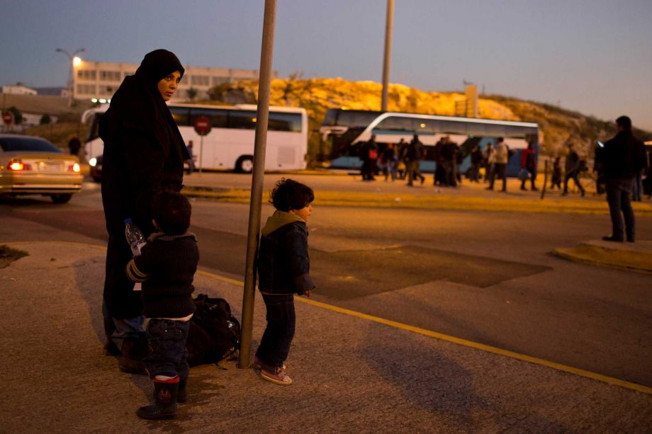 A Syrian woman with her children wait for a bus after their arrival by ferry at the Athens main port of Piraeus early Thursday Dec. 24 2015. The Geneva-based International Organization for Migrants says more than 1 million people have entered Europe