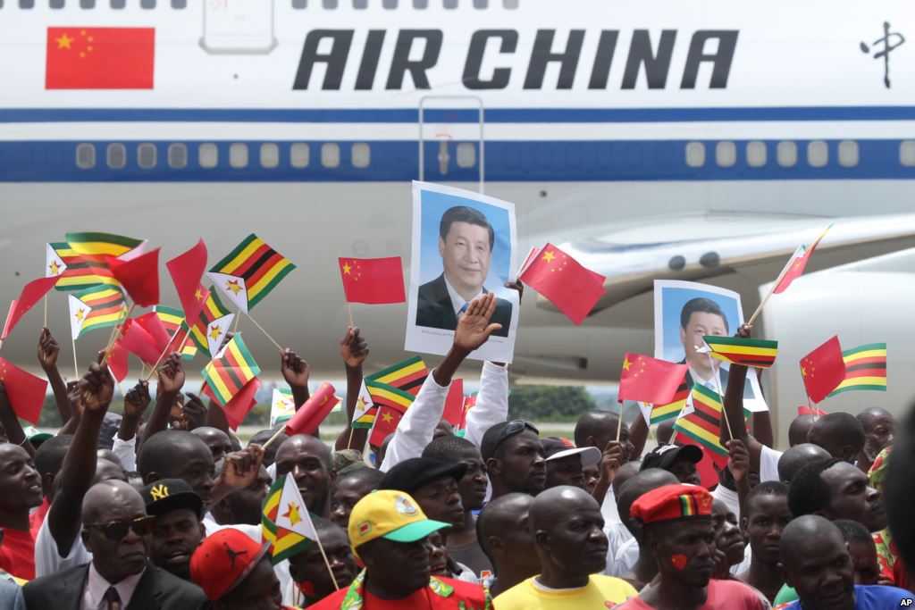 Zimbabweans wave flags while welcoming Chinese President Xi Jinping in Harare Zimbabwe Tuesday Dec. 1 2015