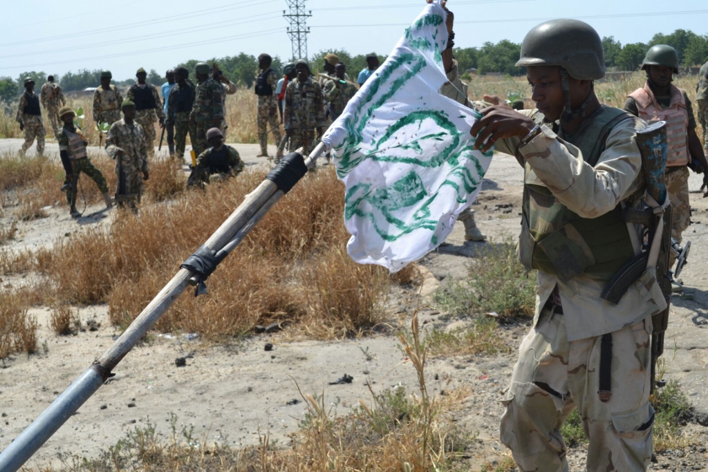 A Nigerian soldier pull down a Boko Haram flag as a mark of victory-PIC:Premium times