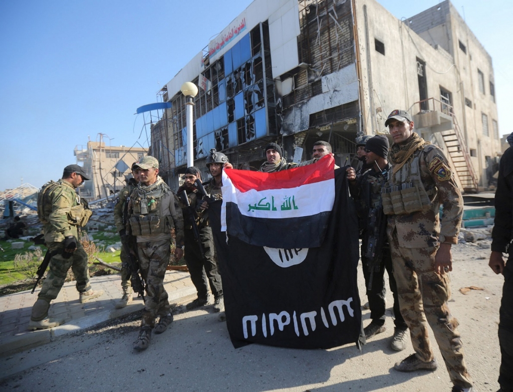 Members of the Iraqi security forces hold an Iraqi flag with an Isis flag which they had pulled down at a government complex in the city of Ramadi