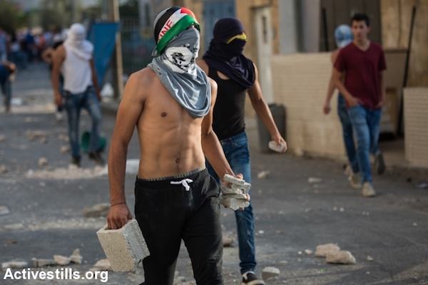 A Palestinian youth prepares to throw pieces of concrete during clashes in the East Jerusalem neighborhood of Shuafat