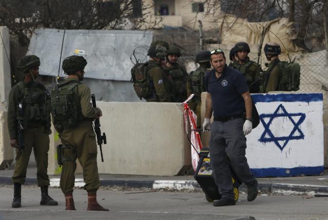 Israeli troops gather at the scene where a Palestinian who the Israeli military said tried to stab an Israeli soldier was killed by Israeli troops near the West Bank city of Hebr