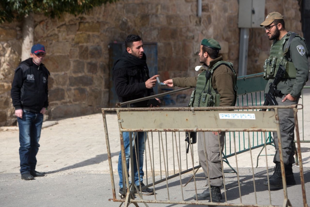 A Palestinian man has his identity checked by Israeli border police patrolling the streets of the West Bank city of Hebron