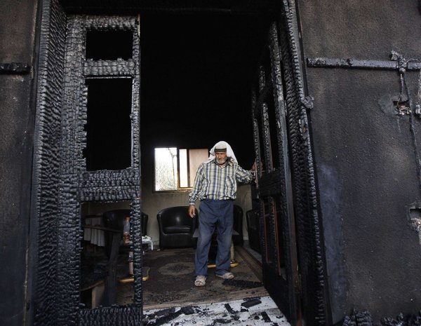 A Palestinian man inspects the West Bank house where a toddler and his parents were killed in a July fire