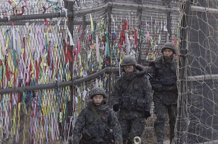 South Korean army soldiers patrol by ribbons wishing for the reunification of the two Koreas attached on the barbed-wire fence in Paju near the border with North Korea