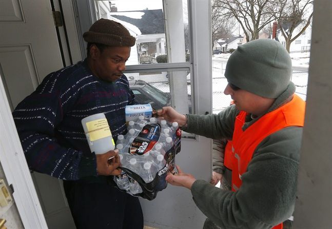 Louis Singleton receives water filters bottled water and a test kit from Michigan National Guard Specialist Joe Weaver as clean water supplies are distributed to residents Thursday Jan. 21 2016 in Flint Mich. The National Guard state employees loca