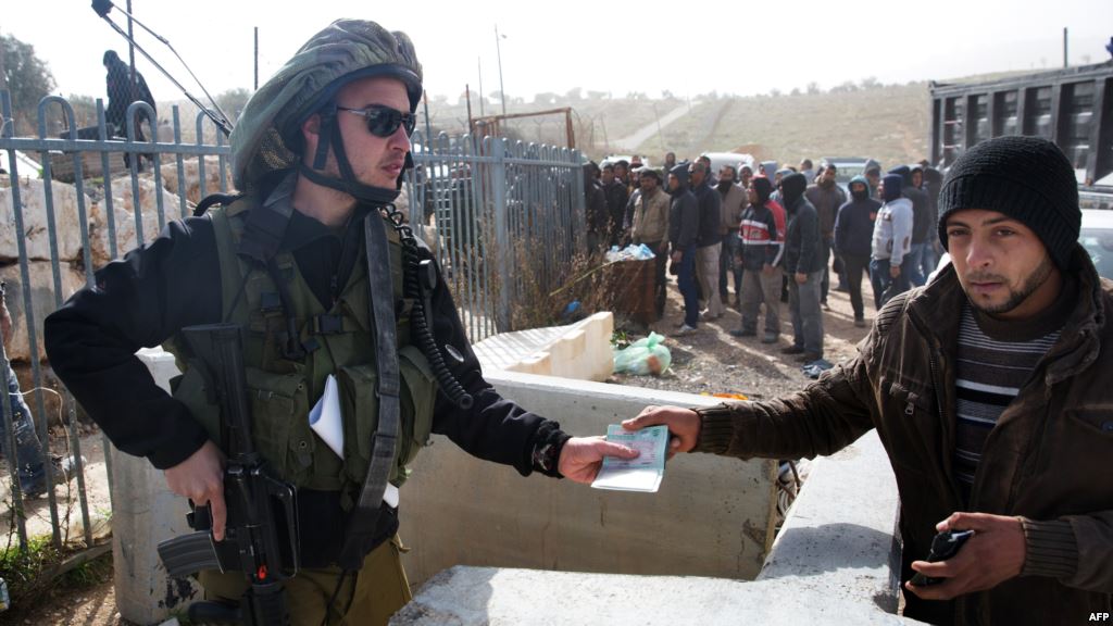 A member of the Israeli security forces hands a Palestinian worker his ID upon his transport out of the Tekoa settlement south of Jerusalem on Jan. 18 2016 after Israeli authorities denied them entry following a stabbing attack