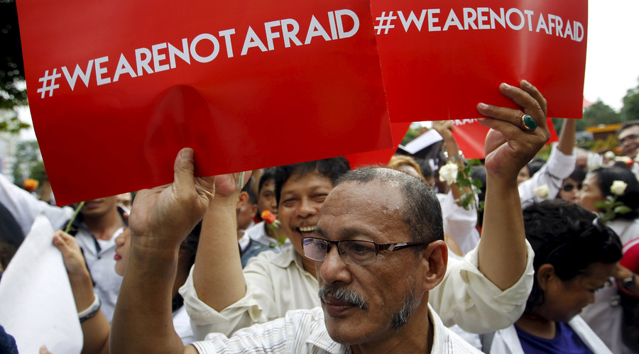 People hold placards during a rally at the scene of Thursday's gun and bomb attack in central Jakarta Indonesia