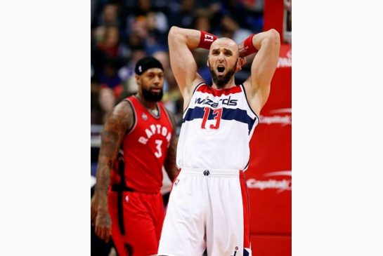 Washington Wizards center Marcin Gortat, from Poland reacts after a play in front of Toronto Raptors forward James Johnson during the first half of an NBA basketball game Friday Jan. 8 2016 in Washington