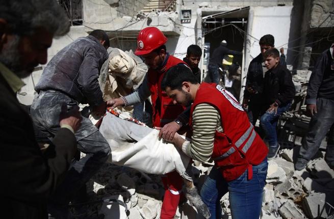 Members of the Syrian Arab Red Crescent and residents search through the rubble for bodies following an airstrike in the rebel-held city of Douma in Eastern Ghouta