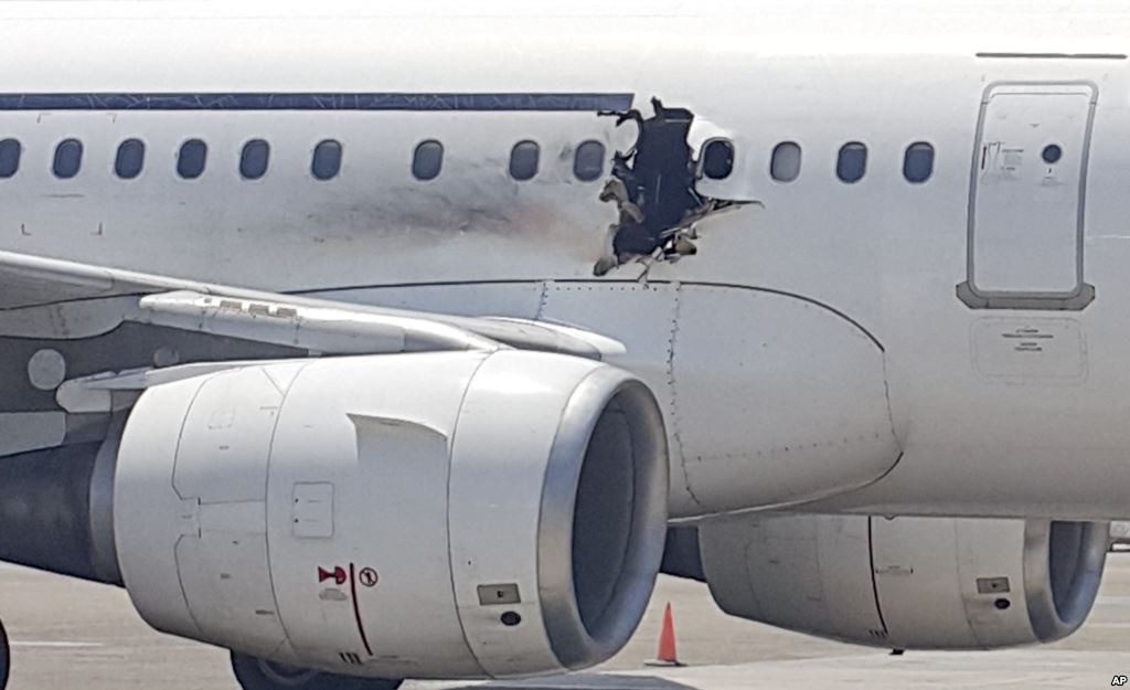 A gaping hole is visible in the side of a plane operated by Daallo Airlines as it sits on the runway of the airport in Mogadishu Somalia Feb. 2 2016