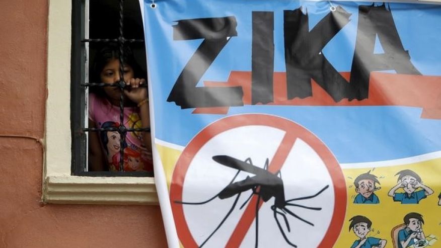 A woman looks on next to a banner as soldiers and municipal health workers take part in cleaning of the streets gardens and homes as part of the city's efforts to prevent the spread of the Zika virus vector