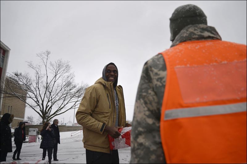 Detroit Pistons power forward Anthony Tolliver smiles while carrying water to a Flint resident's car on Tuesday at Fire Station No. 1 a Water Resource Center on East 5th St in Flint Mich