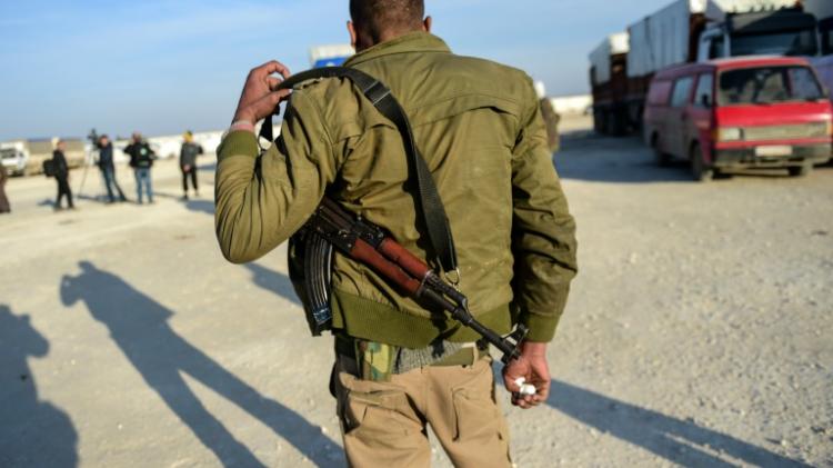 A Syrian opposition fighter watches as people fleeing the embattled city of Aleppo wait in Bab Al Salama near the Turkish border