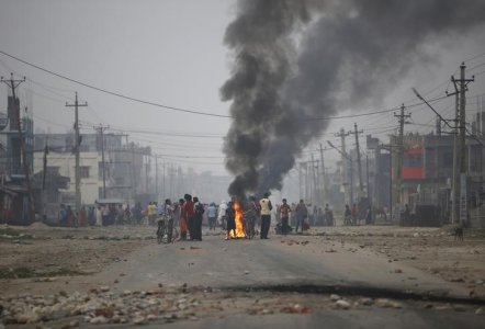 Protesters stand near burning tyres as they gather to block the highway connecting Nepal and India during a general strike called by Madhesi protesters demonstrating against the new constitution in Birgunj Nepal