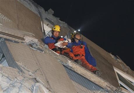 Rescue workers carry a baby swaddled in a cloth from the rubble of a toppled building after an earthquake in Tainan Taiwan Saturday Feb. 6 2016. The 6.4-magnitude earthquake struck southern Taiwan early Saturday toppling at least one high-rise reside