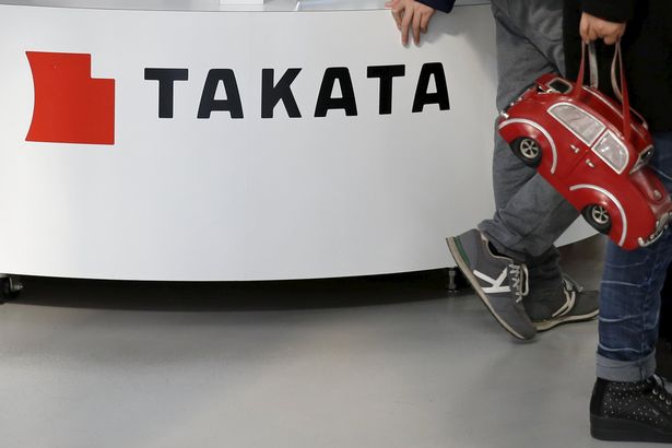 Visitors walk past a logo of Takata Corp