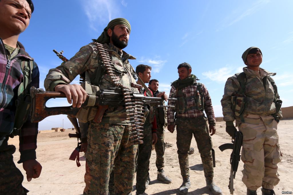 Syria Democratic Forces fighters carry their weapons in a village on the outskirts of al Shadadi town Hasaka countryside Syria Feb. 19 2016