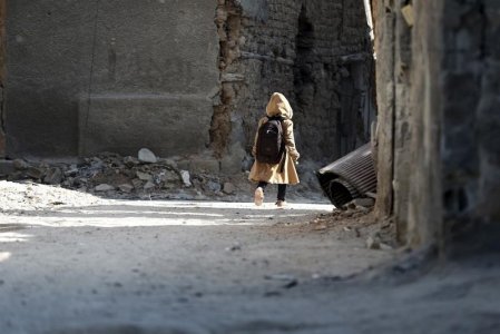 A child carries a school bag near damaged buildings in Harasta in the eastern Damascus suburb of Ghouta Syria