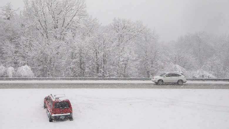 A motorist who slid off the road rests in the median of Interstate 93 during a snowstorm Friday Feb. 5 2016 in Epping N.H