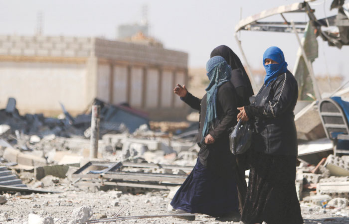 Women walk on rubble in Al Shadadi town in Hasaka province Syria. — Reuters