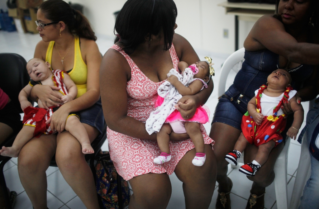 Babies dressed in Carnival outfits born with microcephaly are held by their mothers at a Carnival party held for babies with the condition in a health clinic