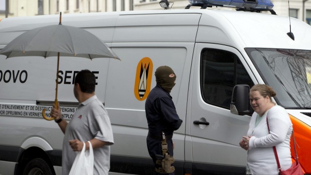 People walk past a bomb squad van outside Antwerp Central train station in Antwerp Belgium on Saturday when homes and