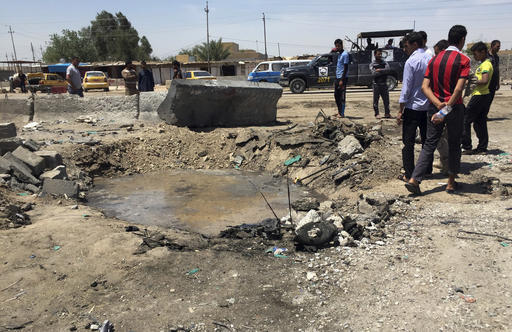 Civilians inspect a crater caused by a car bombing at an open-air market selling fruit vegetables and meat in Baghdad's southeast suburb of Nahrawan Iraq Saturday