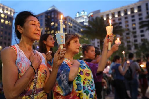 Sam Jitaree left and Devi Thompson of Orlando Fla. hold candles at a vigil for the victims of a mass shooting at the Pulse nightclub at Dr. Phillips Performing Arts Center in downtown Orlando on Monday