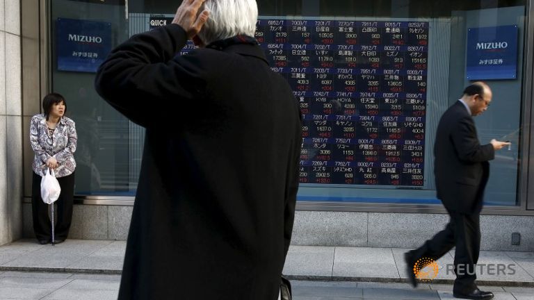 A man looks at an electronic board showing market indices outside a brokerage in Tokyo Japan