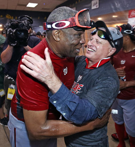 Washington Nationals manager Dusty Baker left gets a hug from Nationals principal owner Mark D. Lerner while celebrating in the locker room after clinching the National League East following a 6-1 win over the Pittsburgh Pi