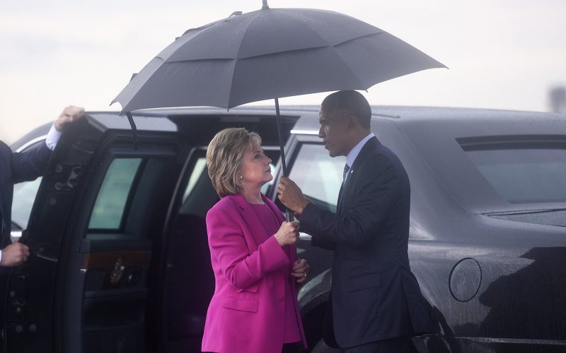 Hillary and Obama outside limo holding umbrella