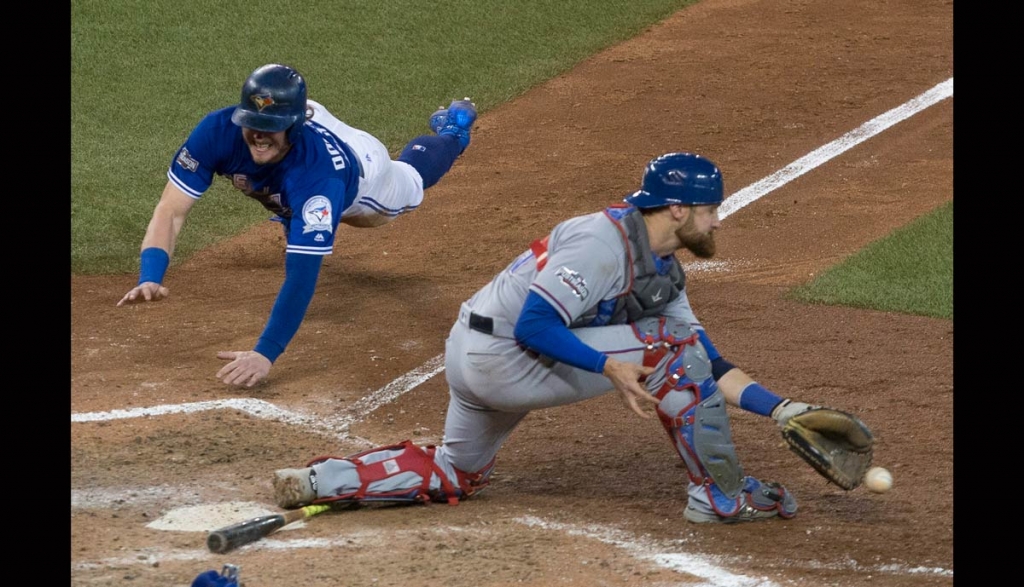 Toronto Blue Jays&#039 Josh Donaldson left scores on a throwing error from Texas Rangers second baseman Rougned Odor as Texas Rangers catcher Jonathan Lucroy gathers up the ball during tenth inning American League Division Series action in Toronto