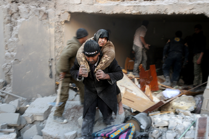 A rescuer carries a woman from the rubble of a building in Aleppo's rebel-held district of al Hamra on 20 November