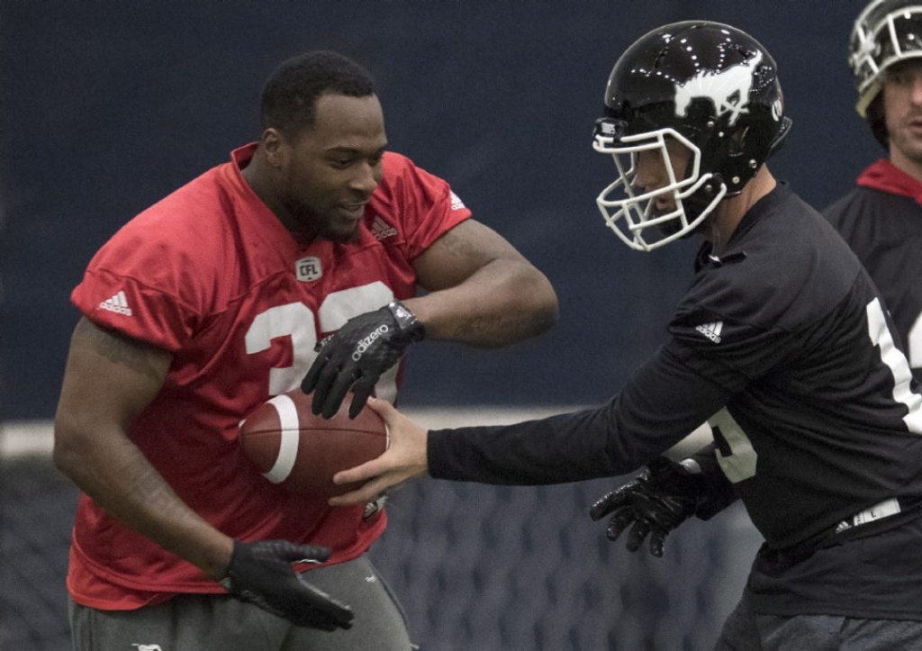 Calgary Stampeders quarterback Bo Levi Mitchell hands off to running back Jerome Messam during a practice for the 104th Grey Cup