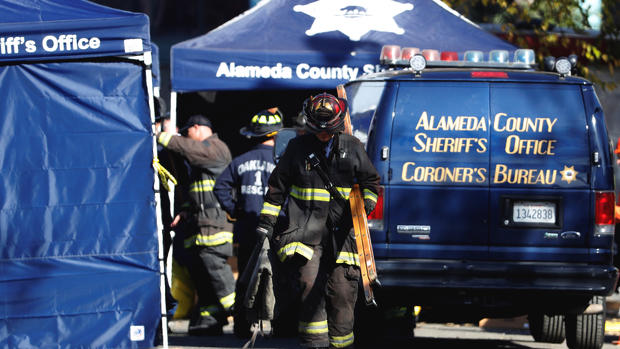 A firefighter carries equipment at the scene of a fire in the Fruitvale district of Oakland California