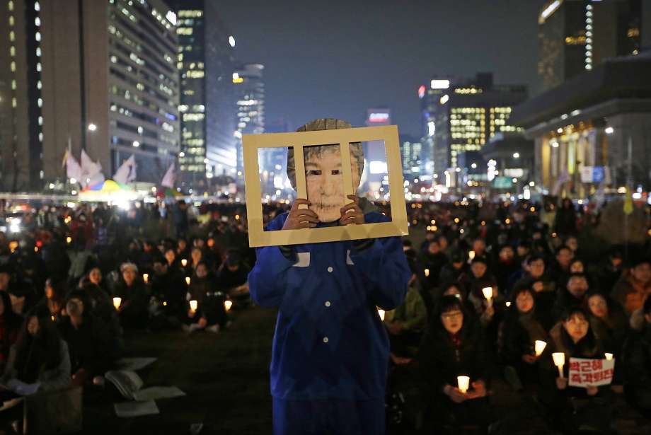 A protester late last month wears a mask of President Park Geun-hye during a rally calling for her impeachment in Seoul. Her opponents are struggling to set a date to strip her of power