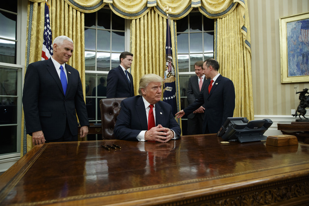 Vice President Mike Pence left watches as President Donald Trump prepares to sign his first executive order Friday Jan. 20 2017 in the Oval Office of