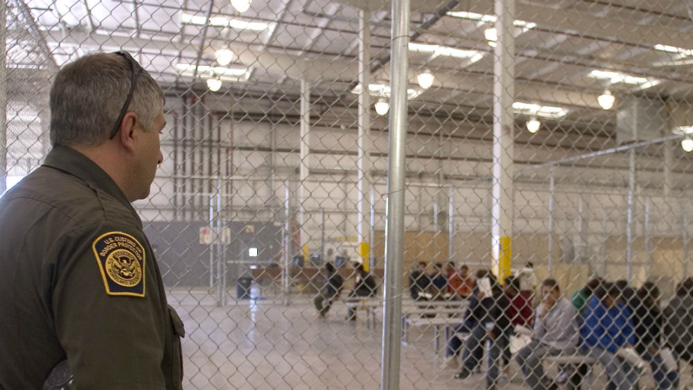 A Border Parol officer watches illegal immigrants in a holding facility. Border Patrol