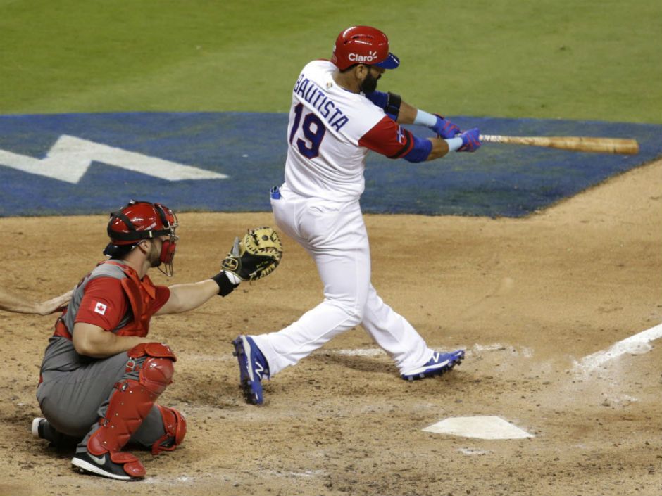 Jose Bautista of defending champion Dominican Republic follows through on his three-run homerun against Canada in World Baseball Classic action Thursday in Miami. Catcher is George Kottaras. Bautista had three hits and four RBI as the Domincan Republic