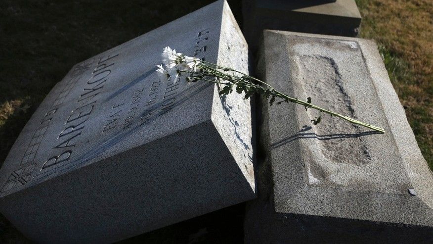 Flowers rest on a damaged headstone at Mount Carmel Cemetery Feb. 28 2017 in Philadelphia. Scores of volunteers are expected to help in an organized effort to clean up and restore the Jewish cemetery where vandals damaged hundreds of headstones. (AP Phot