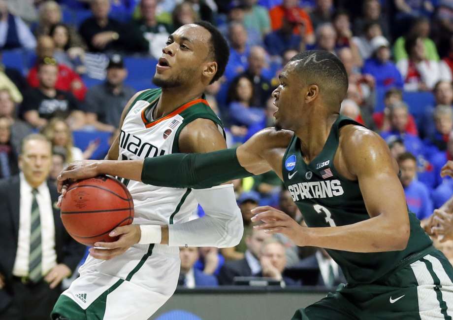 Miami guard Ja'Quan Newton left works to get a shot off against Michigan State guard Alvin Ellis III in the first half of a first-round game in the men's NCAA college basketball tournament in Tulsa Okla. Friday