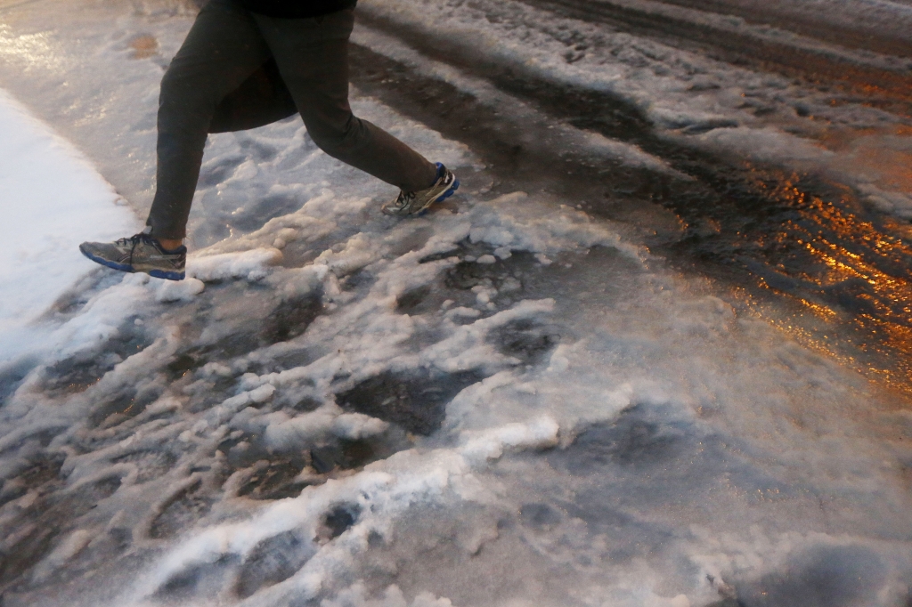 A man leaps over a puddle with snow outside of the Hoboken PATH train station during a snowstorm Tuesday